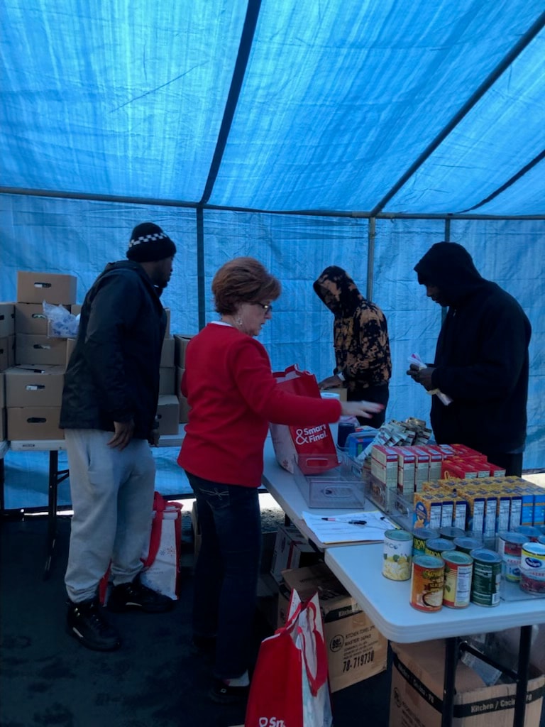 Volunteer presenting ribs and BBQ sauce donations for a food drive
